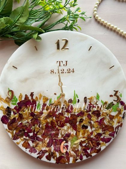 A minimalist design for a resin wall clock, with preserved petals arranged at the bottom. The couple's initials and wedding date are placed at the top, keeping the design clean and elegant.