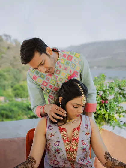 A tender moment between the couple during their Mehendi ceremony, with the groom gently touching the bride's chin.