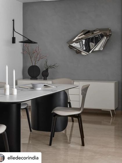 A closer look at the dining area, where the sculptural metal art piece contrasts with the smooth finish of the dining table and the soft curves of the chairs. This juxtaposition of materials and forms is central to my design approach.