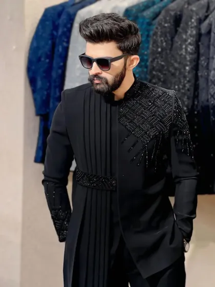 This black indowestern outfit features an asymmetrical cut with a pleated drape and detailed beadwork on the shoulder. I focus on creating unique silhouettes that blend traditional craftsmanship with modern tailoring.
