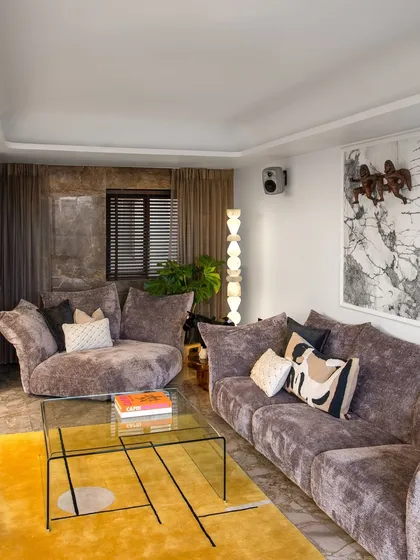 This wide shot reveals the full composition of the art collector's living room. The layout is designed to facilitate conversation while showcasing prized sculptures and paintings, proving that a home can be both a gallery and a sanctuary.
