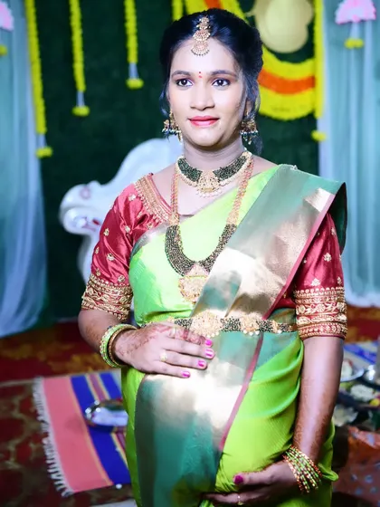 A full portrait of Sonu at her baby shower. The makeup is balanced to complement her vibrant green and red saree and heavy jewellery.