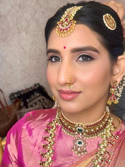 A classic Muhurtham look. I created sharp, defined eyes and a soft pink lip to balance the richness of her pink silk saree and traditional gold jewelry.