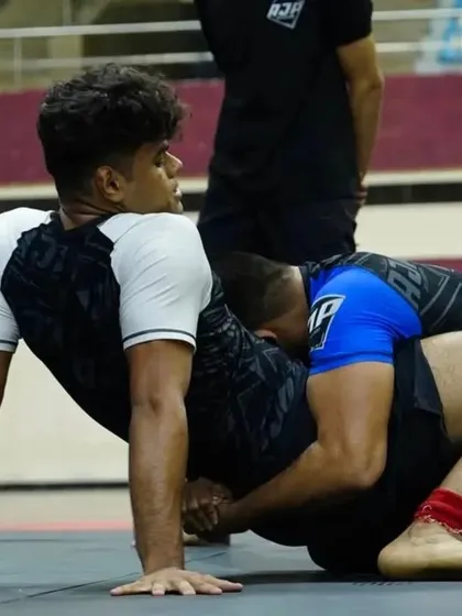 A moment of transition during a competitive grappling match. Our fighter works to improve his position, constantly striving to get better.
