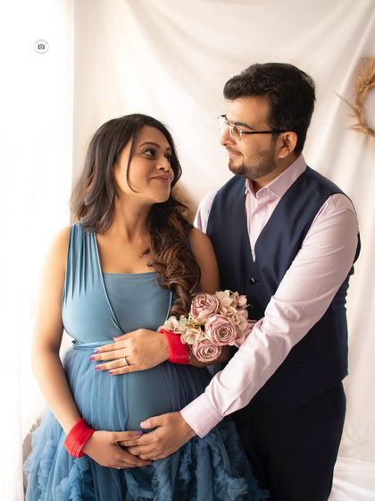 The loving gaze between a couple during their maternity session. Her blue gown and the soft studio lighting create a romantic feel.