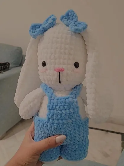 Meet Fluffy, a custom-ordered bunny plushie. This amigurumi toy features adorable details like handmade blue overalls and matching bows, all crafted from soft white yarn for the perfect huggable friend.