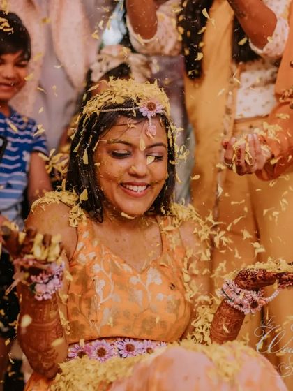 The bride's radiant smile as she's showered with petals during her Haldi. It's a moment of pure bliss and the beginning of a beautiful journey.