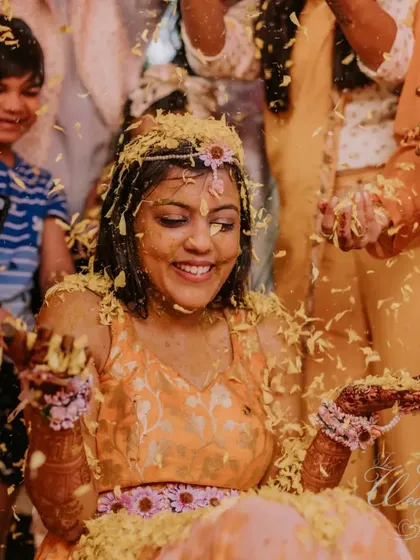 The bride's radiant smile as she's showered with petals during her Haldi. It's a moment of pure bliss and the beginning of a beautiful journey.