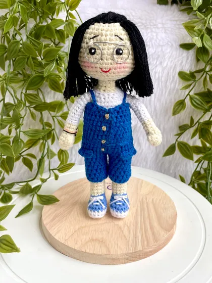 A lovely replica doll in a blue jumpsuit with matching shoes. The details, like her glasses and hairstyle, were carefully crafted to match the photos provided. These dolls can be made to stand on a wooden base.