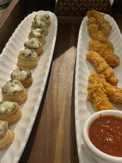 A platter showcasing two of our popular passed appetizers. On the left are creamy mushroom vol-au-vents, and on the right are crispy chicken tenders with a dipping sauce, demonstrating the variety we offer.