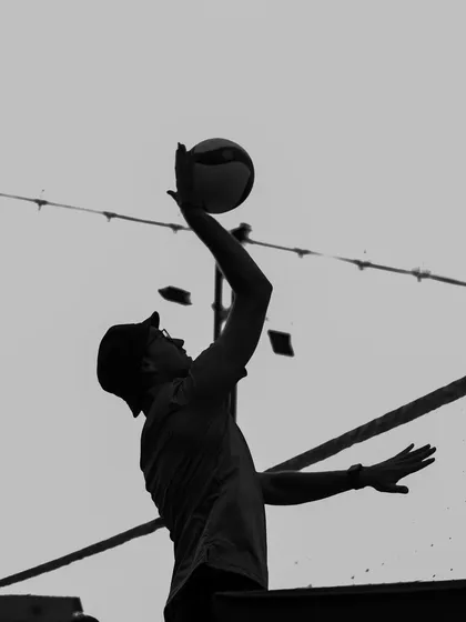 A player connects with the ball during a serve, a moment of perfect timing frozen in black and white.