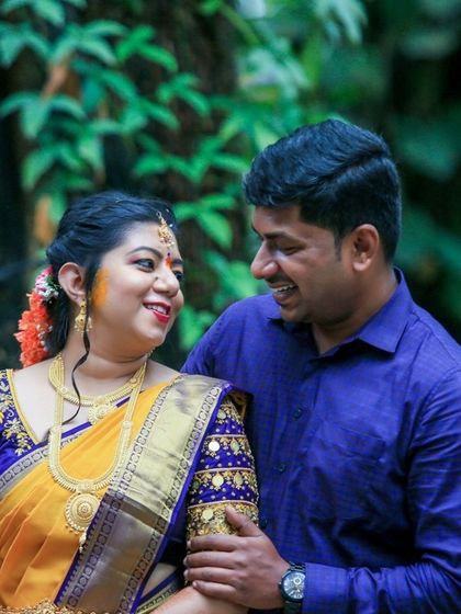 A happy, candid shot of a couple sharing a moment during their outdoor engagement ceremony, surrounded by lush greenery.