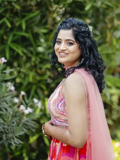 This Haldi hairstyle features natural curls in a half-updo, adorned with a small floral accessory. It's a fun, fresh, and practical style that keeps the hair managed during the ceremony.