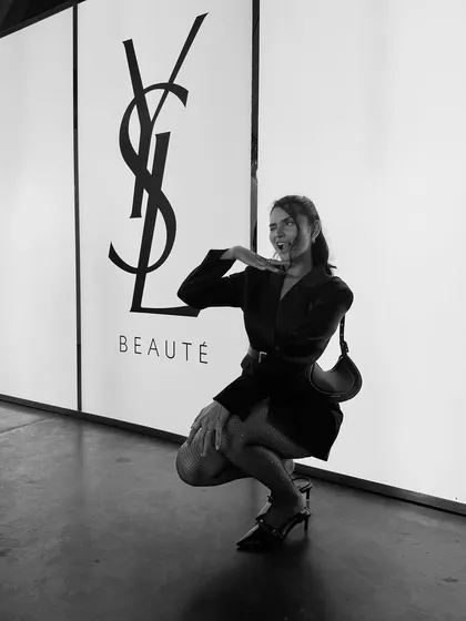 Posing with the iconic YSL logo, creating a strong brand association in a playful way.