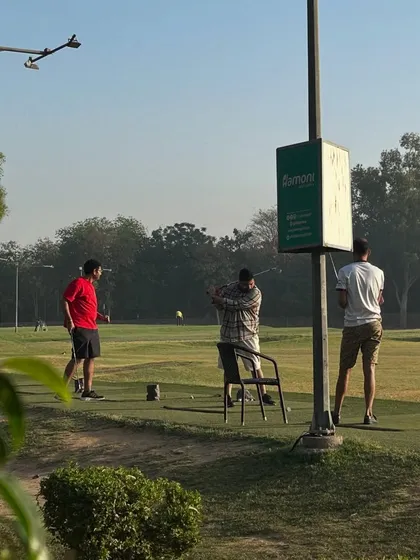 A view of the range from a distance, showing three golfers practicing near our Hamoni sign.