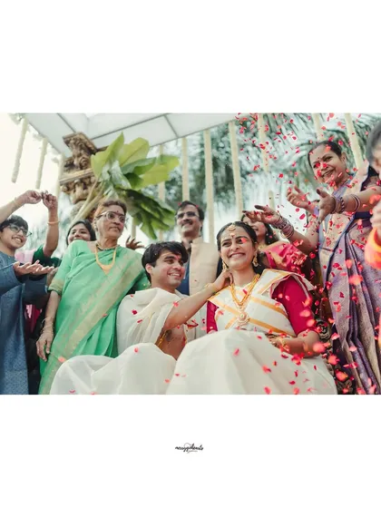 A wide shot capturing the joy of the family as they bless the newly married couple with a shower of petals.
