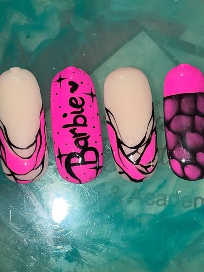 A sample set of Barbie-themed press-on nails, featuring the logo, abstract patterns, and a snakeskin effect.