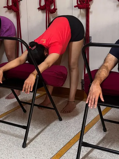To de-stress, a supported forward bend over a chair can be profoundly calming. Resting the torso and head allows the back muscles to release and the mind to quiet. This is part of a sequence designed to bring the body and mind into a state of balance and peace.