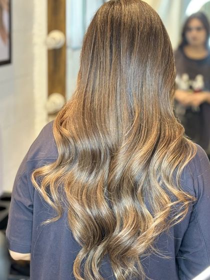 This back view highlights the seamless blend of brown tones in this client's hair. The soft waves add texture and volume, creating a look that is both glamorous and effortlessly chic.