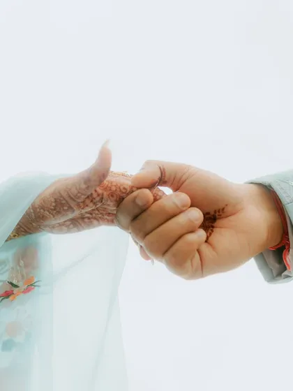 A close-up of the couple holding hands, with traces of henna and turmeric. It's the small details that often tell the biggest stories of love and tradition.