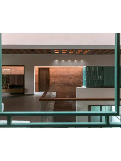 A view from the upper level of 'An Earthy Affair', looking down into the double-height space. The green-painted railings and perforated ceiling details add character and visual interest.