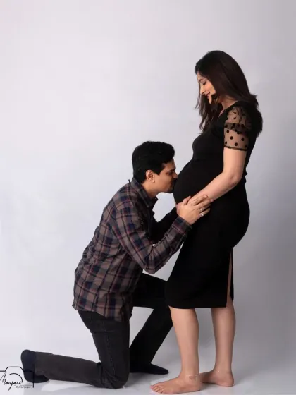 A classic and tender bump kiss. The simple black dress and white background create a clean, modern, and timeless look.