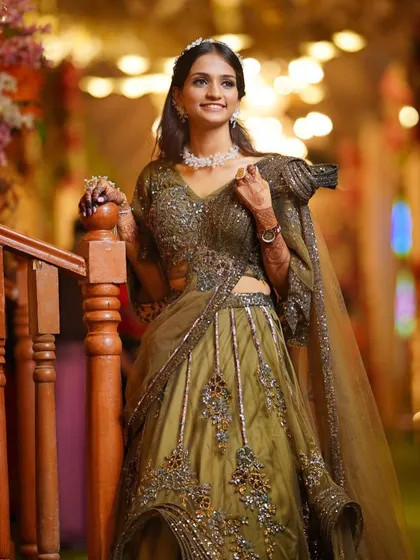 A doll-like look for a brother's wedding, featuring a beautiful olive green lehenga and soft, romantic makeup.