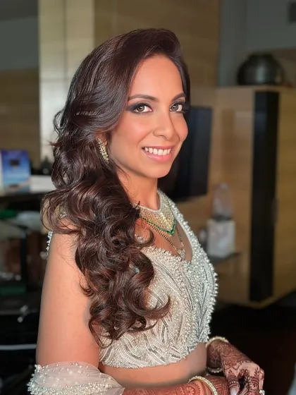 This bride's look is all about classic Hollywood glamour. The soft waves and radiant makeup create a sophisticated and timeless look that pairs beautifully with her white and silver outfit.