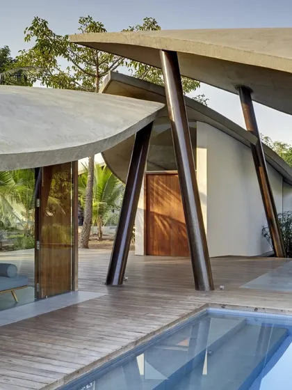 For 'The Leaf House', a weekend retreat, the form of the building itself was inspired by nature. The organic, leaf-shaped concrete shells shelter the living spaces while opening up to the landscape, creating a home that feels like a natural extension of its environment.