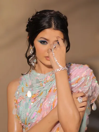 A dramatic pose highlighting the colorful eye makeup and sparkling jewelry.