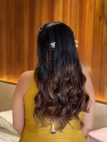 A beautiful half-up style for a baby shower, featuring soft waves, delicate braids, and a hanging latkan accessory for a traditional touch.