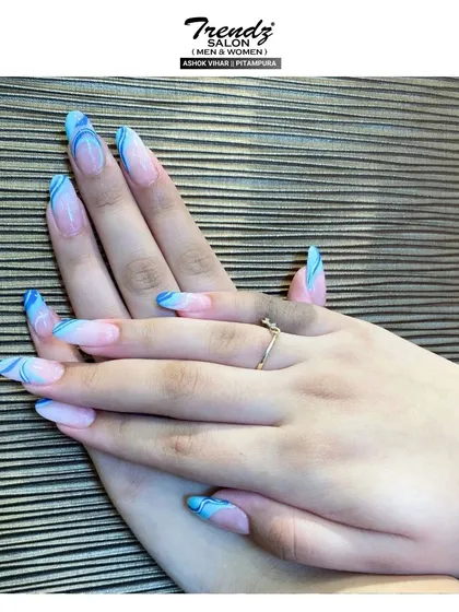 This is a close-up of the fun and stylish blue French manicure with white swirl accents. The bright color and creative pattern make it a standout choice for a modern nail design.