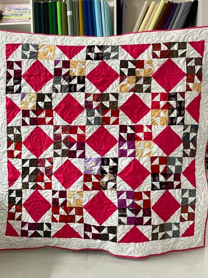 A complex patchwork quilt with bright pink diamond accents.