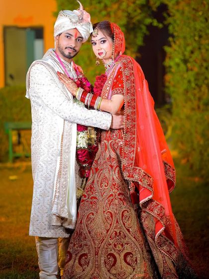 A variation of the wedding portrait, with the bride in a different red lehenga, showing the different looks a couple might have during their events.