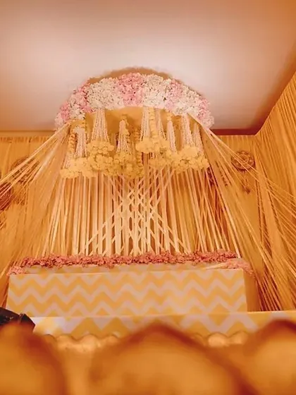 A different angle of the Haldi stage, highlighting the intricate arrangement of drapes and hanging floral strings.