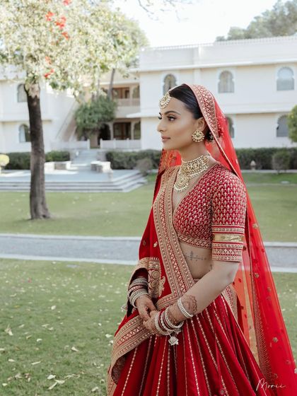 A beautiful outdoor shot of the bride in her red Sabyasachi lehenga. The makeup is clean and classic, perfect for a destination wedding.