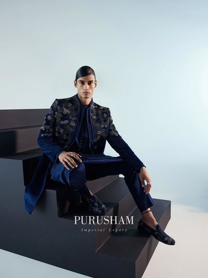 Another view of the navy blue velvet bandhgala, this time seated to show its structure and form. It's a luxury ensemble that sets a new standard for sophistication.