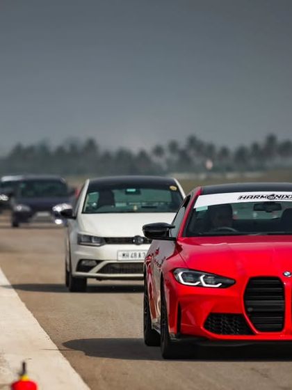 A stunning red BMW M4 leads a parade of performance cars down the track, with fans lining up to watch. This is the kind of hero moment we create for both drivers and spectators.