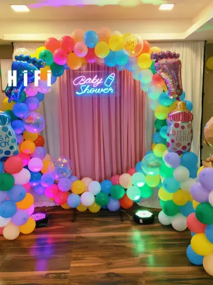 A vibrant and colorful baby shower setup with a rainbow balloon circle. This cheerful decor includes "It's a Boy" and "It's a Girl" foil balloons, making it perfect for a gender reveal party too.
