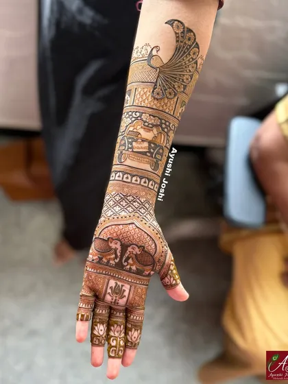 A side view of the engagement mehendi, focusing on the arm with the car drive caricature and the elegant peacock above it.