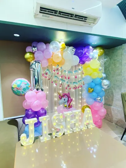 A magical Unicorn theme for a first birthday, featuring pastel balloon columns, a unicorn foil balloon, and light-up marquee letters.