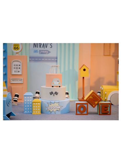 Another view of the vehicle-themed cake and prop setup, showing the 'Vroom' and 'Boom' comic-style signs.