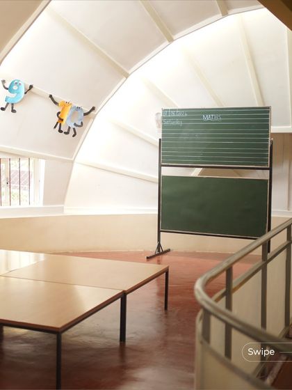 The interior of the kindergarten building, with its high, curved ceiling and low windows at a child's eye level. The space feels vast and playful, like a giant toy.