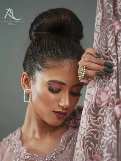 This close-up portrait focuses on the mood of the collection. It highlights the makeup, the elegant updo, and the texture of the embroidered fabric, creating an image that is both a beauty shot and a detailed garment feature.