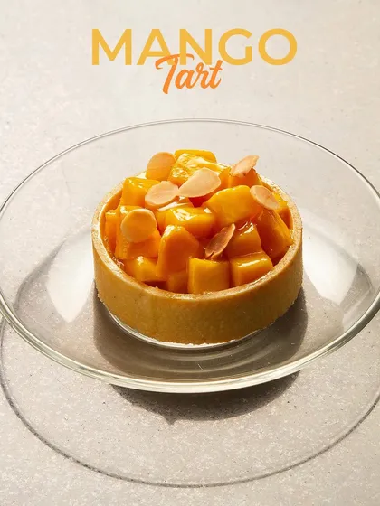 A delicate Mango Tart, with a buttery crust filled with mango cream and topped with fresh mango pieces and almond slivers. A perfect summer dessert.