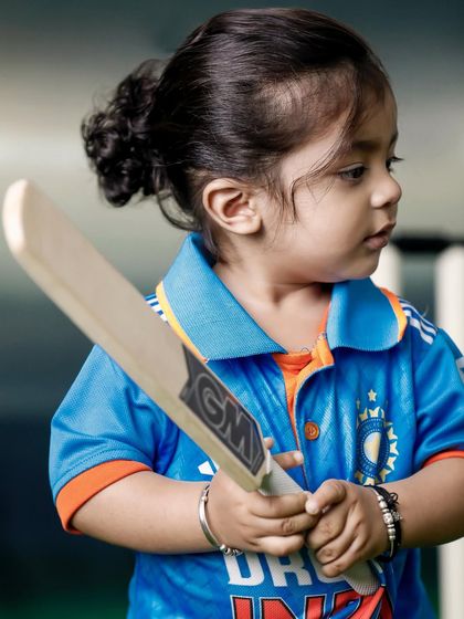 A profile shot of a toddler holding a cricket bat, looking focused and determined. This portrait captures the serious side of a little sportsman.