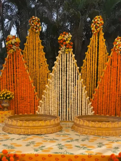 For this haldi ceremony at a farmhouse, I created a unique backdrop with triangular panels made entirely of fresh marigold and tuberose strings. The two golden urlis in the front are ready for the ceremony's rituals.