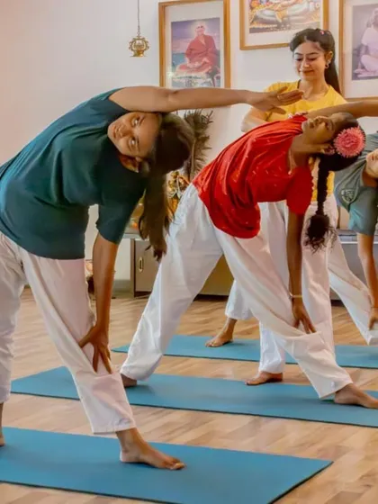Students practice Trikonasana (Triangle Pose) in a group setting. This standing posture strengthens the legs, stretches the hips and spine, and improves overall balance and stability.