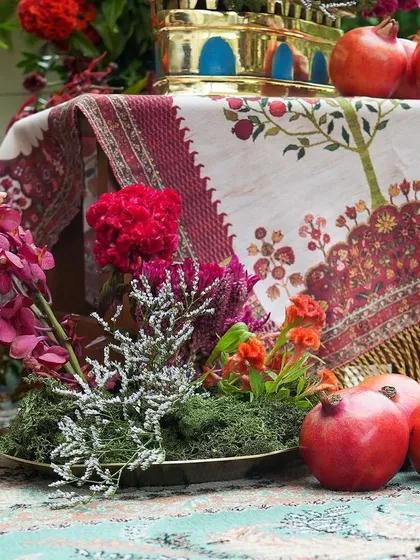 A tablescape detail showing a mix of orchids, celosia, and pomegranates. We explore how to combine different types of flowers and natural elements for a sophisticated look.