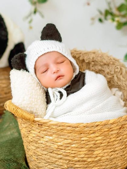 A close-up of the baby in a knitted panda bonnet, looking absolutely adorable. I have a wide collection of handmade outfits and bonnets for our sessions.